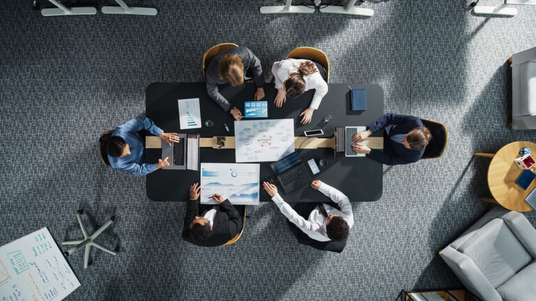 Top Down View: Diverse Professionals Working on Business Statistics Reports and Digital Plans in an Office